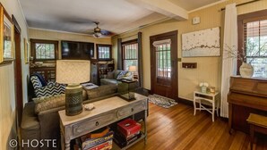 A cozy living room with a sofa, coffee table, and bookshelves. There is a wooden door and a window with curtains. - 4BR Dog Friendly Mtn Retreat With Gym! (Colorado Springs)