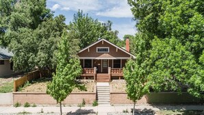 A two-story house with a front porch, a chimney, and a small front yard with trees and a gravel pathway. - 4BR Dog Friendly Mtn Retreat With Gym! (Colorado Springs)