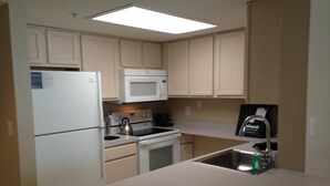 A compact kitchen with a refrigerator, microwave, stove, and sink. - National at Ballston Metro (Arlington)