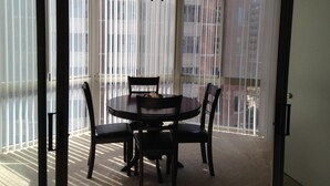 A balcony with a round table and four chairs, large windows with blinds, and a ceiling fan. - National at Ballston Metro (Arlington)