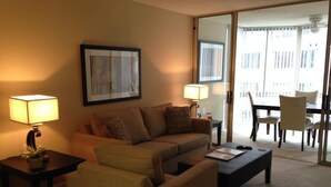 A living room with a sofa, two side tables with lamps, a coffee table, and a dining area with chairs and a table. - National at Ballston Metro (Arlington)