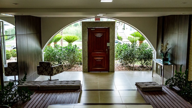 A hotel entrance with a wooden door, a bench, and a tiled floor. - Apto de luxo em Jurerê internacional REN002 (Florianópolis)