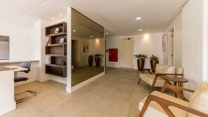 Un interior moderno con una recepción, zona de estar y una pared espejada.