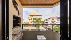 Un balcón con un lavamanos de piedra, un taburete blanco y vistas a edificios cercanos.