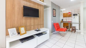 Una sala de estar moderna con un televisor de pantalla plana, un sillón rojo y un mueble blanco para entretenimiento.