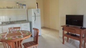 Una cocina compacta con refrigerador, una mesa de comedor con sillas y un mueble de televisión de madera.