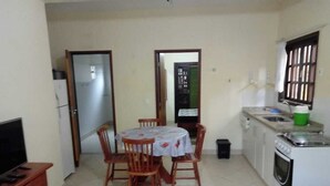Un espacio habitable compacto con comedor, kitchenette y televisor sobre un mueble de madera.