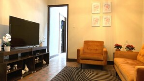 A living room with a flat-screen TV, a sofa, a chair, and a patterned rug. - Vintage Home near Larcomar (Urb Cercado de Miraflores)