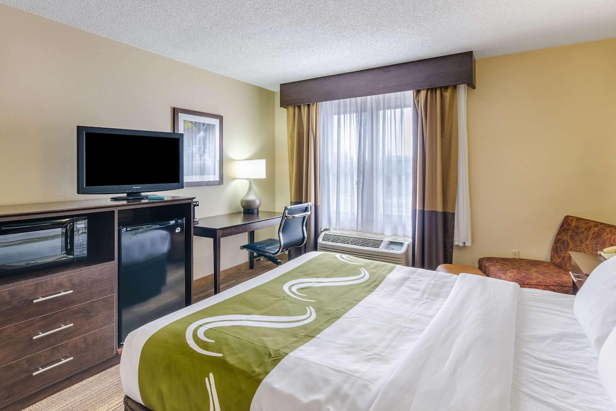 Ein Hotelzimmer mit Bett, Schreibtisch mit Computer, Fernseher, Mikrowelle und Klimaanlage.