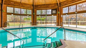 Ein großer, überdachter Pool mit Glaswänden und Holzboden, mit Stufen zum Ein- und Ausstieg.