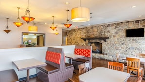 Ein Restaurant mit Sitzecken, Tischen und einer Steinwand mit Kamin.