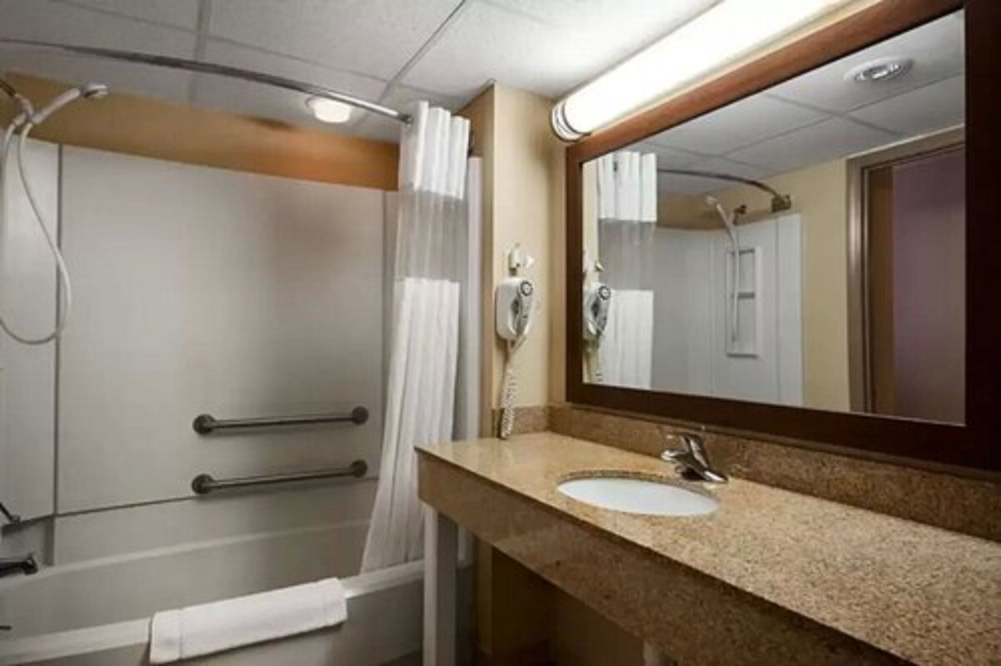 A bathroom with a sink, mirror, and shower area.