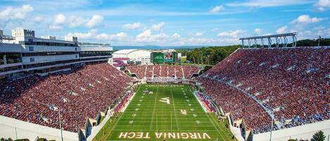 A stadium with a football field, seating areas, and a large crowd.