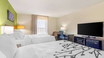 Habitación de hotel con dos camas, un escritorio, un televisor de pantalla plana, un minibar y una ventana con cortinas.