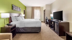 Une chambre d’hôtel comprenant un lit, un bureau avec une lampe, une télévision et un mini-bar.