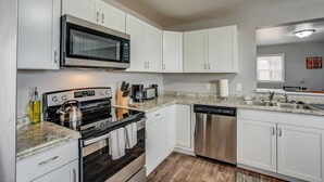 A modern kitchen with white cabinets, stainless steel appliances, and a granite countertop. - 2BR Olympic Training Center Dog-friendly (Colorado Springs)