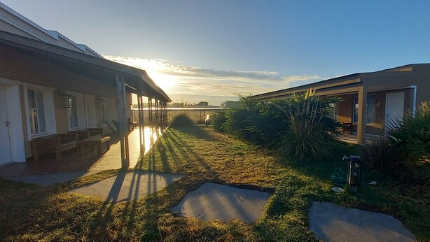 A pathway leading to a building with a covered porch and a small garden area with grass and plants. - Altos de Adonai (Lonquimay)