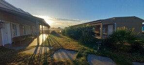 A pathway leading to a building with a covered porch and a small garden area with grass and plants.