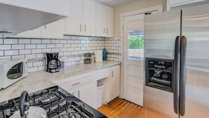 A modern kitchen with white cabinets, a stainless steel refrigerator, a gas stove, and a coffee maker. - 3brdowntownwalk to Everywhere & Bars W/fire pit (Colorado Springs)