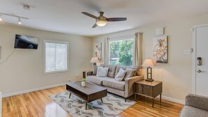 A living room with a sofa, a coffee table, a TV, a ceiling fan, and a door with a keypad lock. - 3brdowntownwalk to Everywhere & Bars W/fire pit (Colorado Springs)