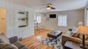 A spacious living room with a wooden floor, a ceiling fan, a dining area with a table and chairs, and a sofa. - 3brdowntownwalk to Everywhere & Bars W/fire pit (Colorado Springs)