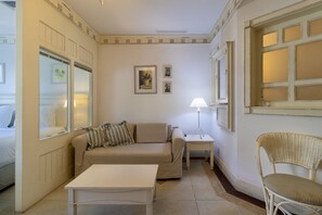 Una habitación con sofá, una mesa pequeña, una silla, una lámpara y una ventana con vistas.