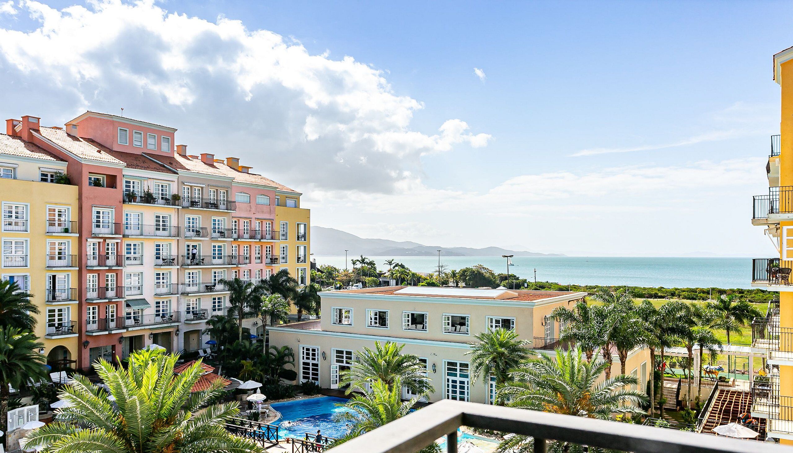 Un hotel con varios balcones con vistas a una piscina y al mar.