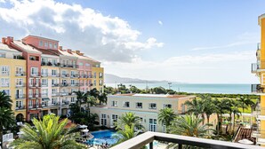Un hotel con varios balcones con vistas a una piscina y al mar.