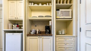 Una cocina compacta con nevera, microondas y cafetera sobre la encimera.