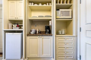 Una cocina compacta con nevera, microondas y cafetera sobre la encimera.