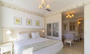 Habitación de hotel con una cama grande, un rincón de estar con una silla y una puerta que da a otra habitación.