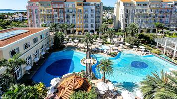 A resort with a large pool, multiple buildings, and palm trees.