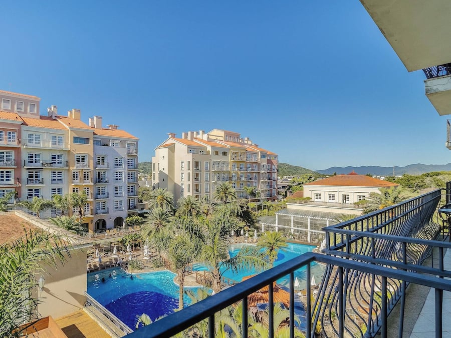 Un hôtel doté d’une piscine, de plusieurs balcons et offrant une vue sur les bâtiments environnants.