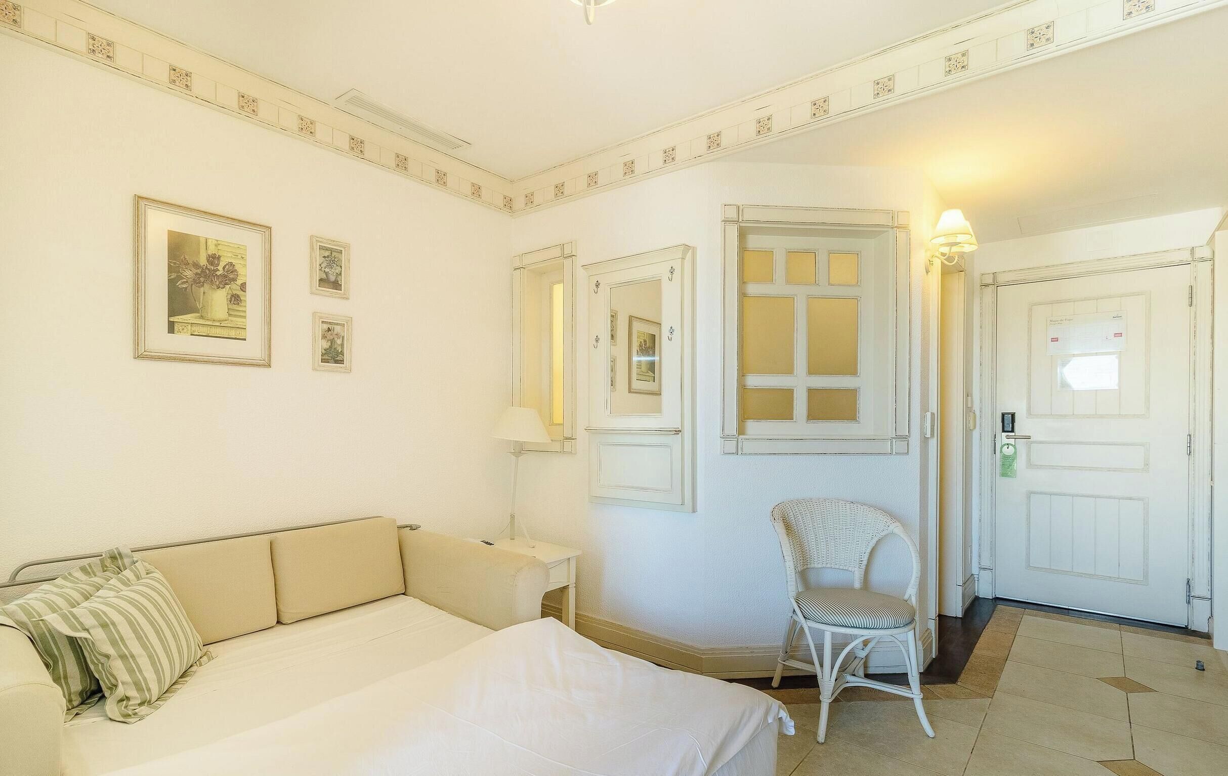 Una habitación de hotel con cama, una silla, un escritorio y una puerta.