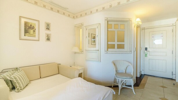 Una habitación de hotel con cama, una silla, un escritorio y una puerta.