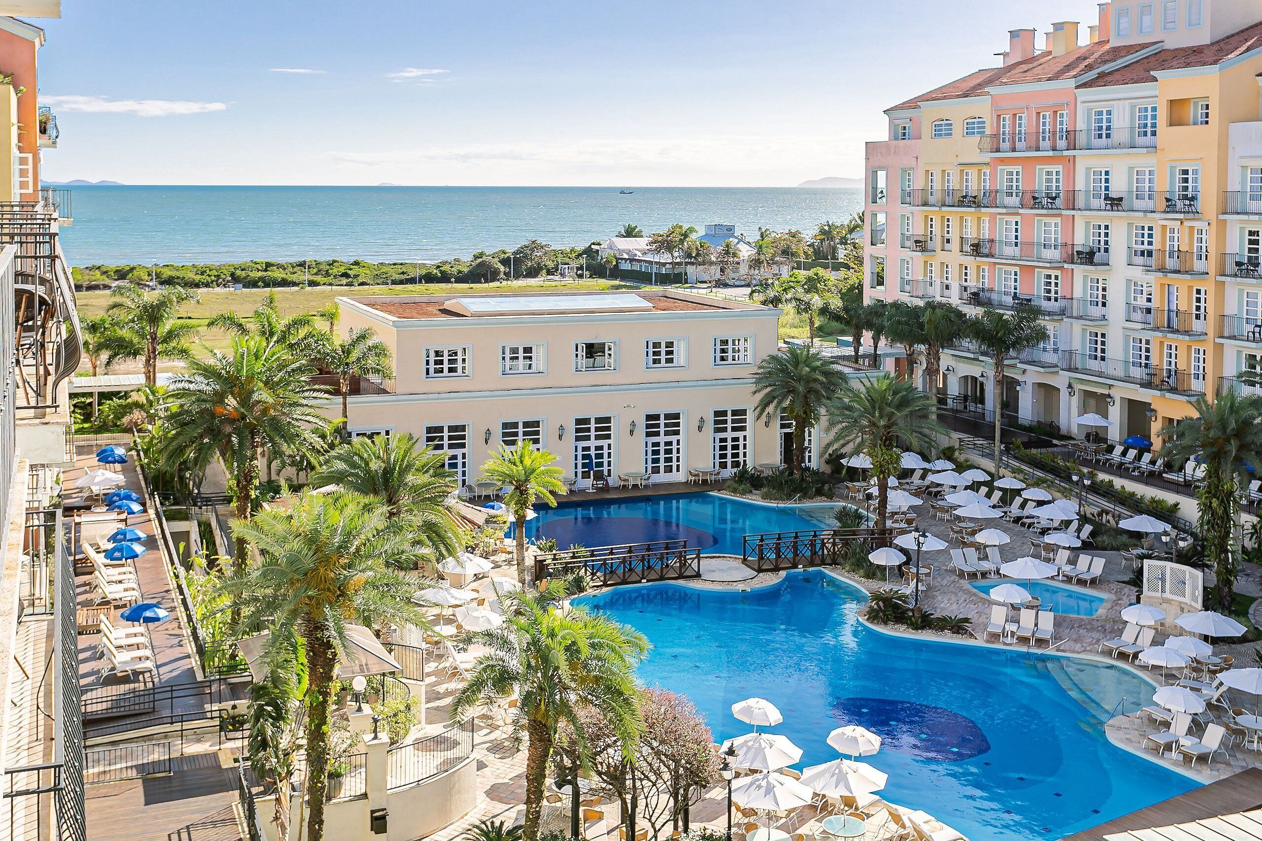 A hotel with a pool, balconies, and a view of the sea.