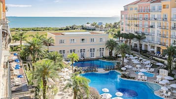 A hotel with a pool, balconies, and a view of the sea.
