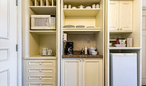 A compact kitchen with a microwave, coffee maker, and a refrigerator.