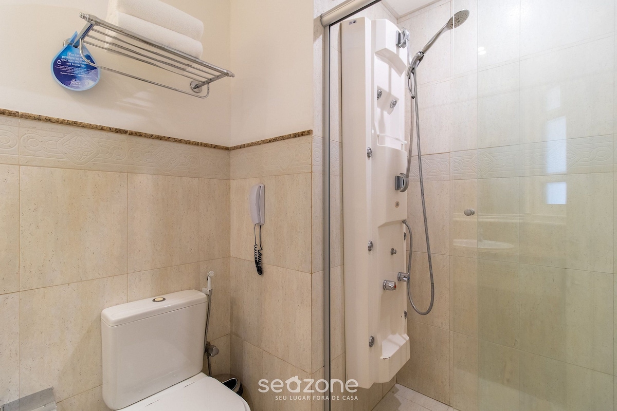 Un baño con inodoro, ducha con puerta de vidrio y toallero con un objeto azul.