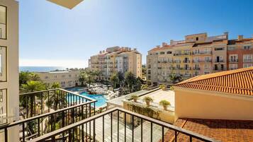 A hotel with a pool, balconies, and a view of the sea.