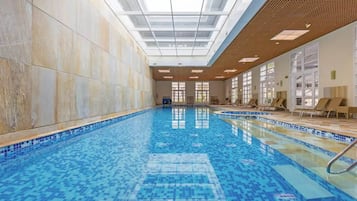 Ein Hallenbad mit gefliesten Wänden und einer Dachfensterdecke.