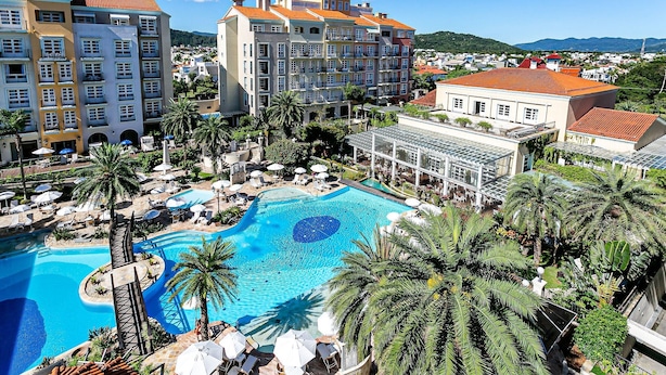 Un resort con piscina, palmeras y vistas a la ciudad.