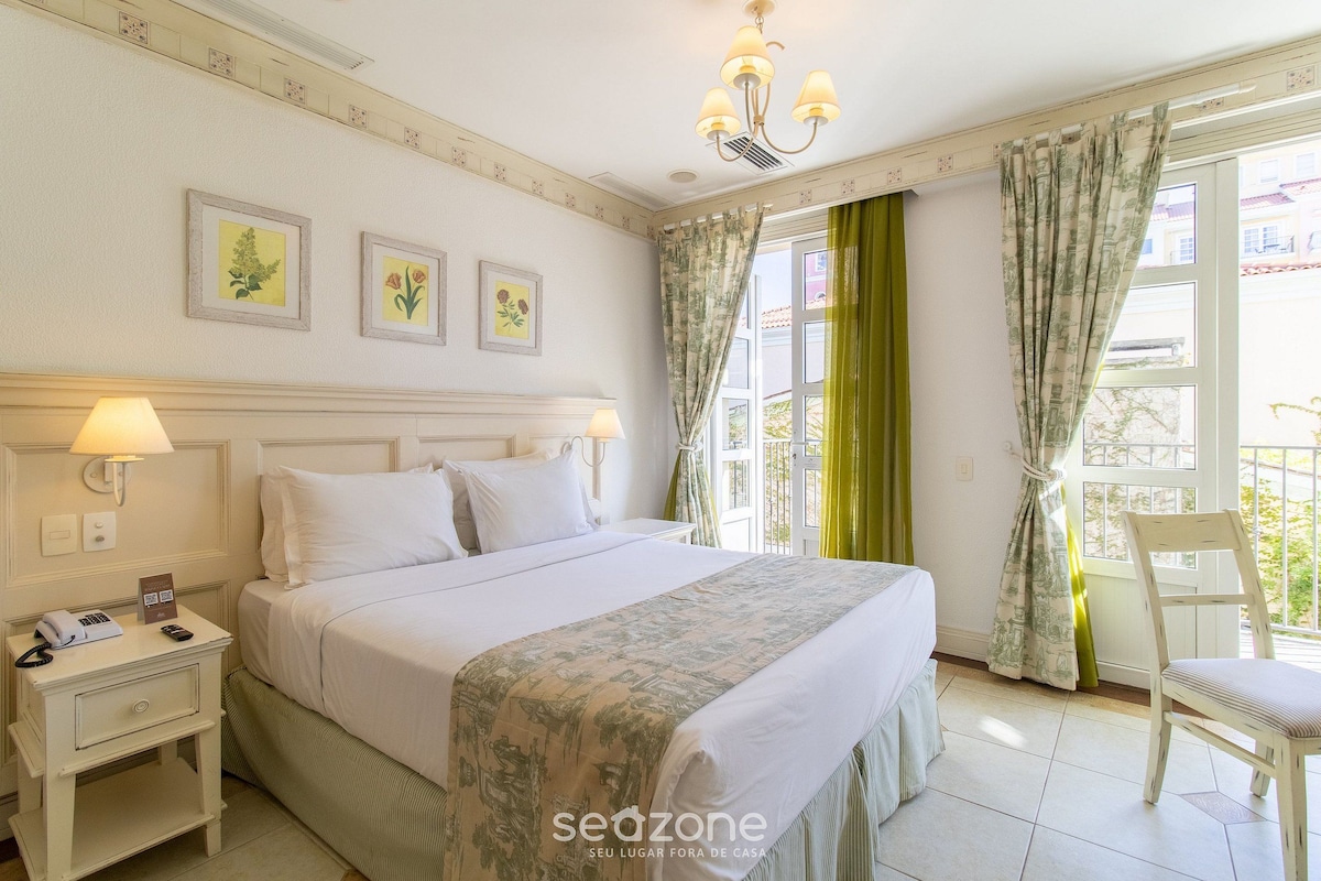 A hotel room with a bed, bedside lamps, a nightstand, a chair, and a window with curtains.