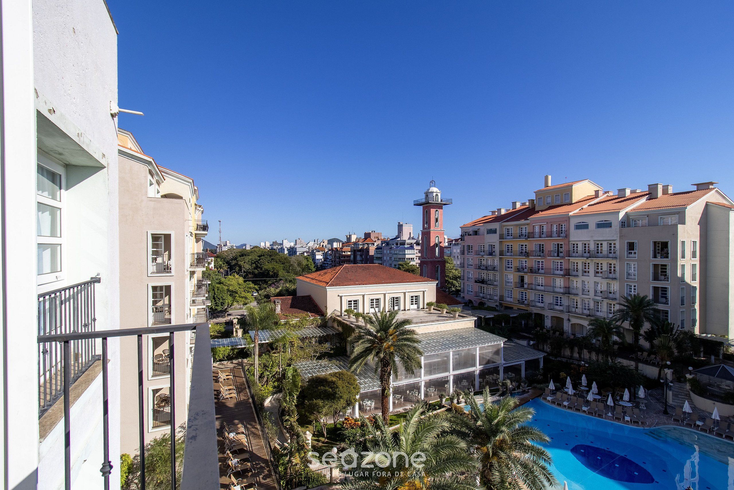 A hotel with a pool, a lighthouse, and a cityscape in the background.