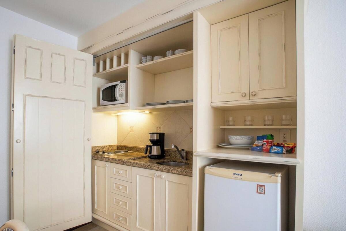 A compact kitchenette with a microwave, coffee maker, and a refrigerator.