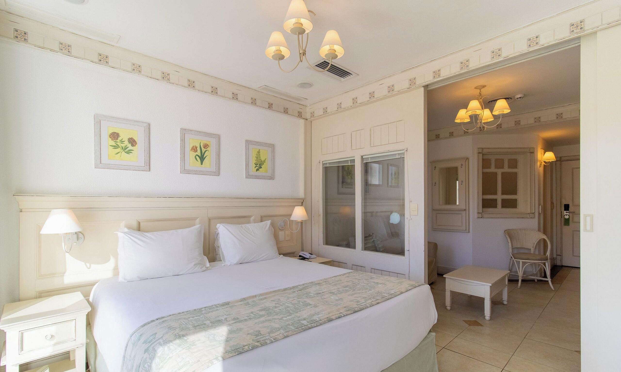 A hotel room with a large bed, a sitting area, and a door leading to a bathroom.