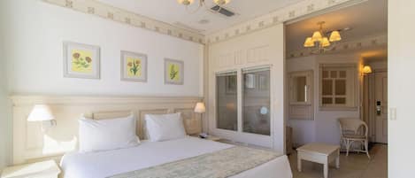 A hotel room with a large bed, a sitting area, and a door leading to a bathroom.