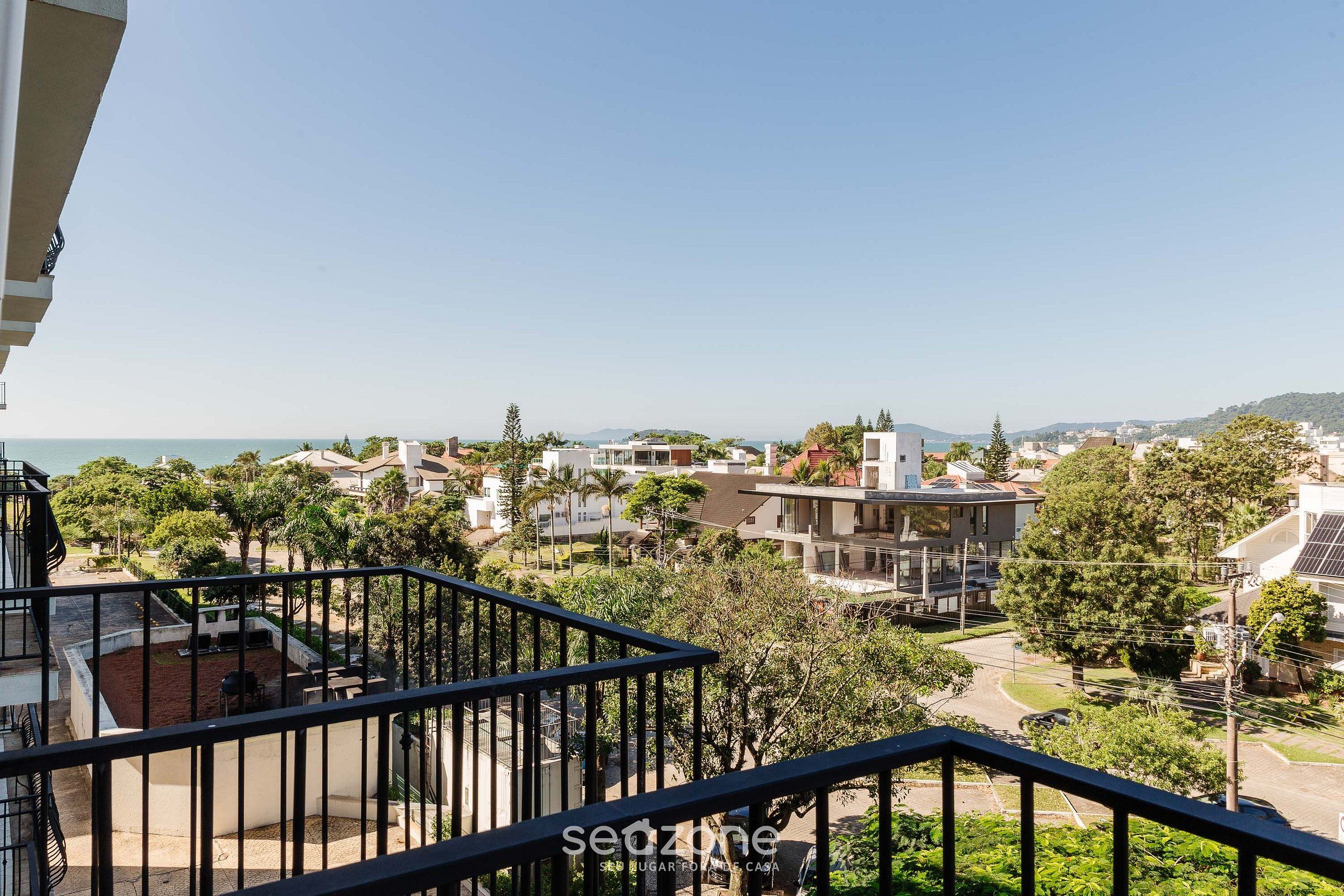 A residential area with a view of the sea, a balcony with a railing, and various buildings.