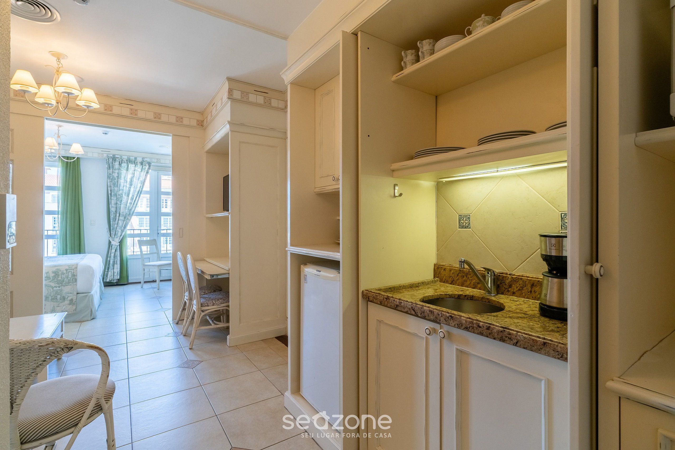 Cocina con lavabo, encimera y armarios.  Hay una zona de comedor con sillas y una mesa.