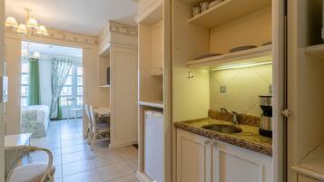 Cocina con lavabo, encimera y armarios. Hay una zona de comedor con sillas y una mesa.